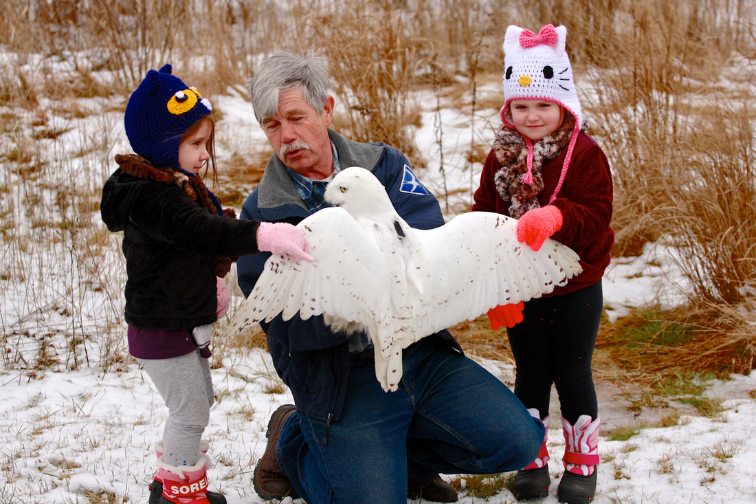 Norman Smith and his two granddaughters holding a snowy owl